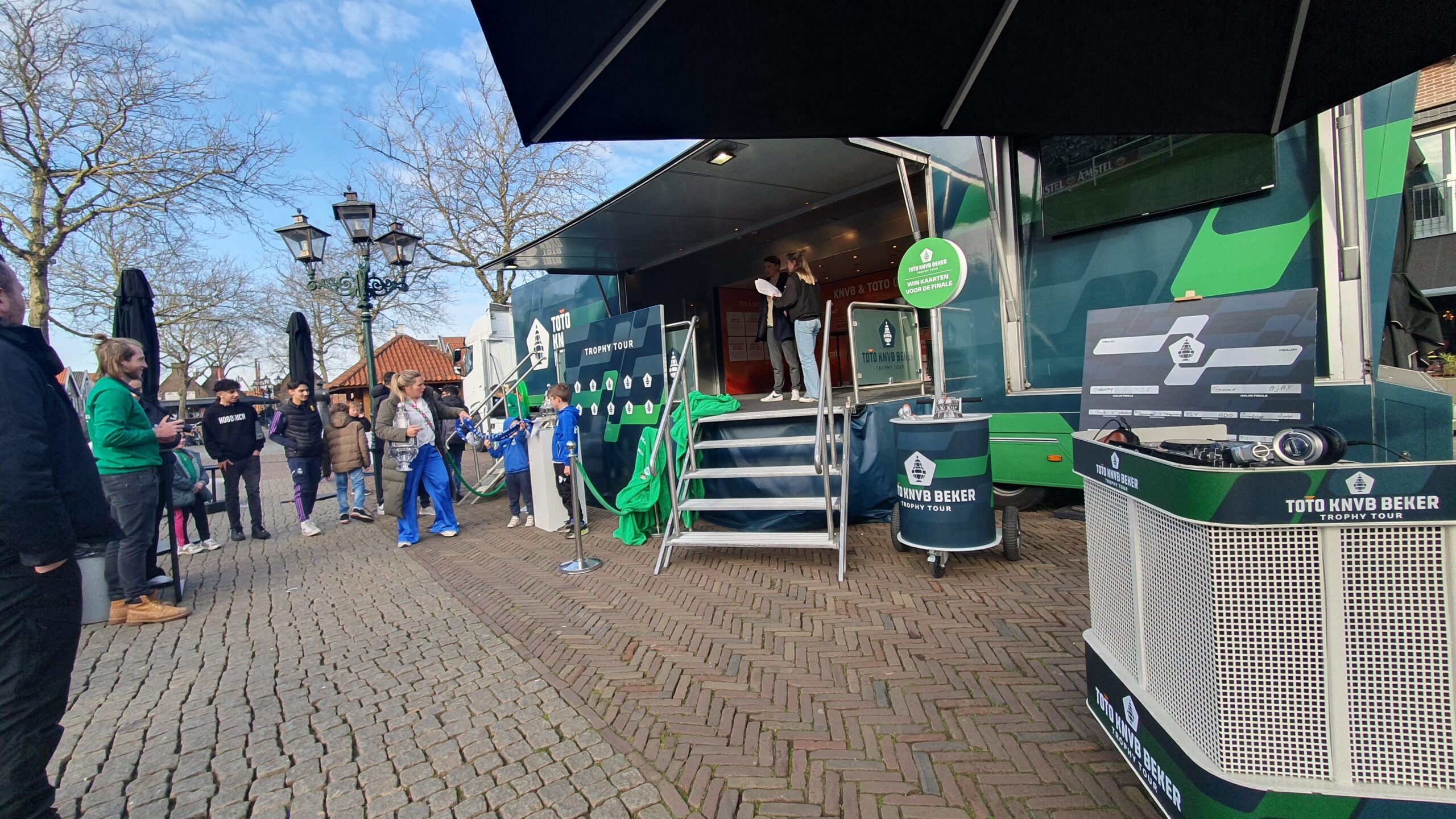 De BeatKit als DJ-station in de belettering van de TOTO KNVB Beker Trophy Tour, opgesteld op een dorpsplein met publiek eromheen